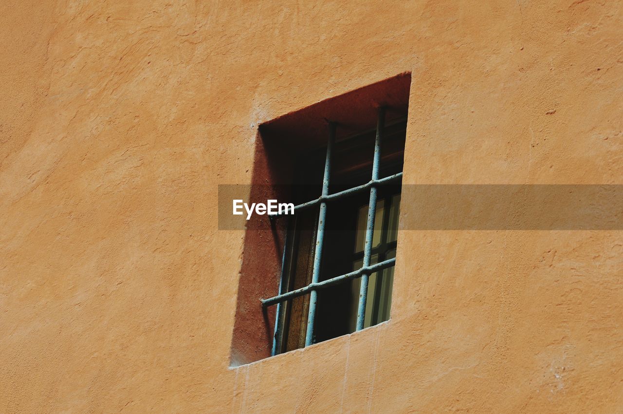 Low angle view of window on orange wall