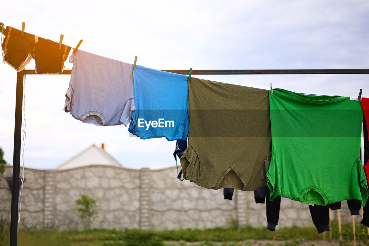 Clean colorful clothes t shirts hanging to dry on a laundry line outdoors, housework