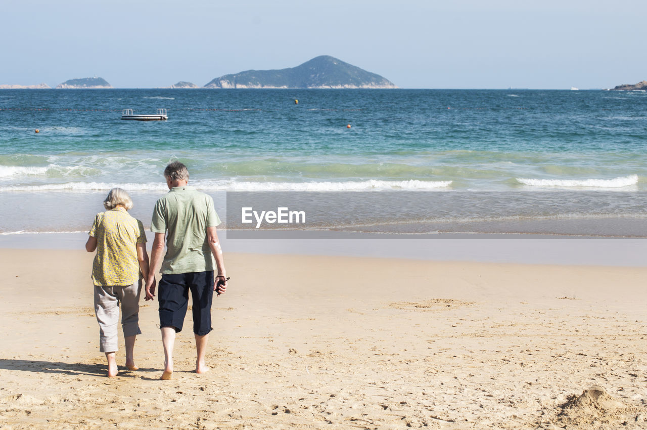 REAR VIEW OF PEOPLE ON BEACH