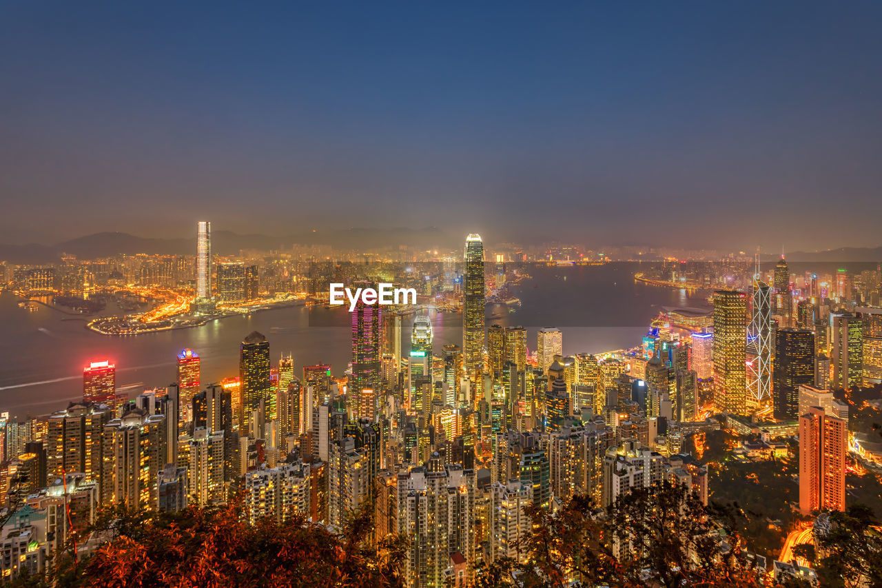 Illuminated modern buildings in city against sky at night