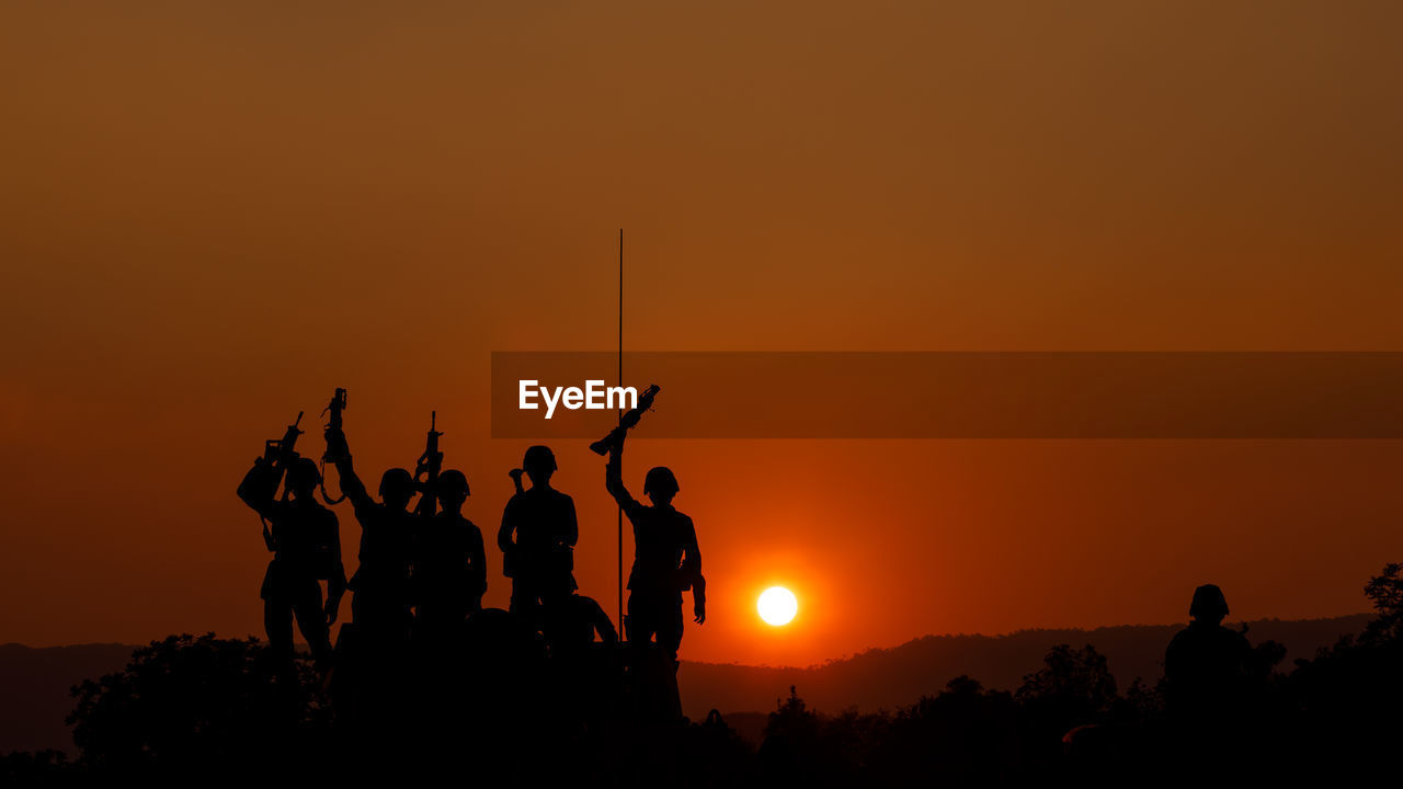 Silhouette group of special forces sodiers hold the guns on tank to indicative of their victory 