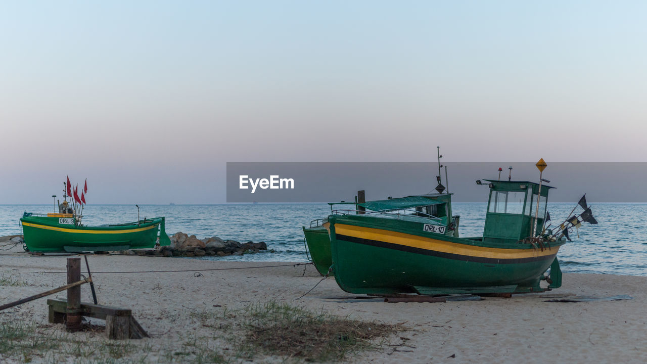 BOATS MOORED ON SHORE AGAINST SKY