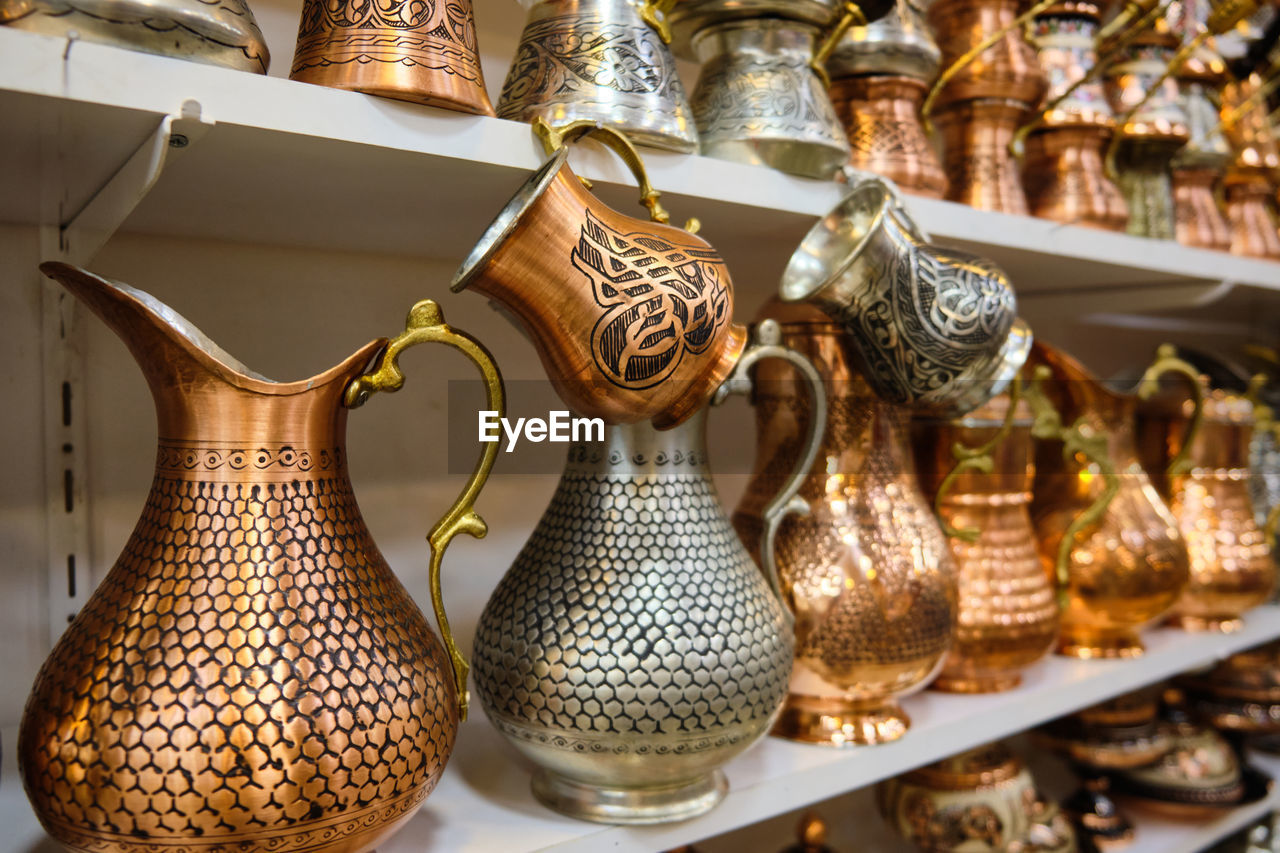 Lots of copper handmade jugs and cezves at shelf of a traditional middle-eastern souvenir store