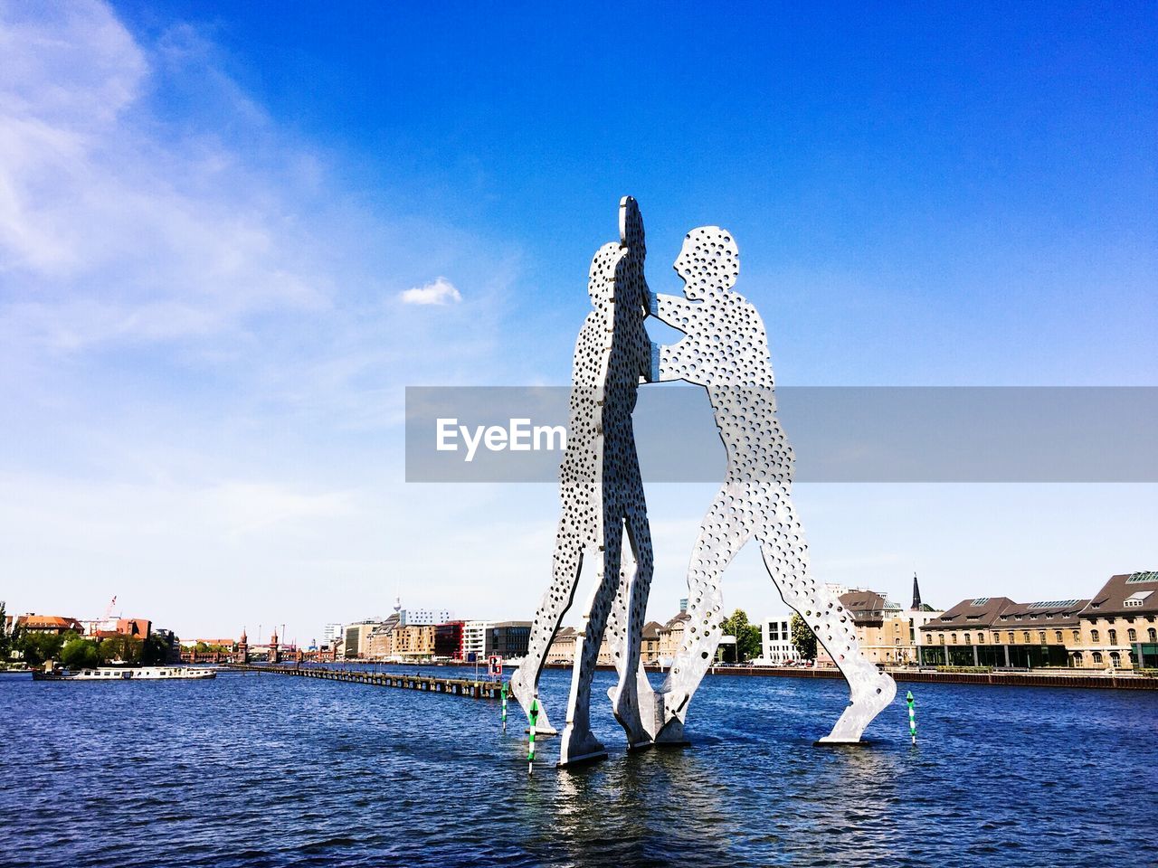 Molecule men amidst spree river against sky