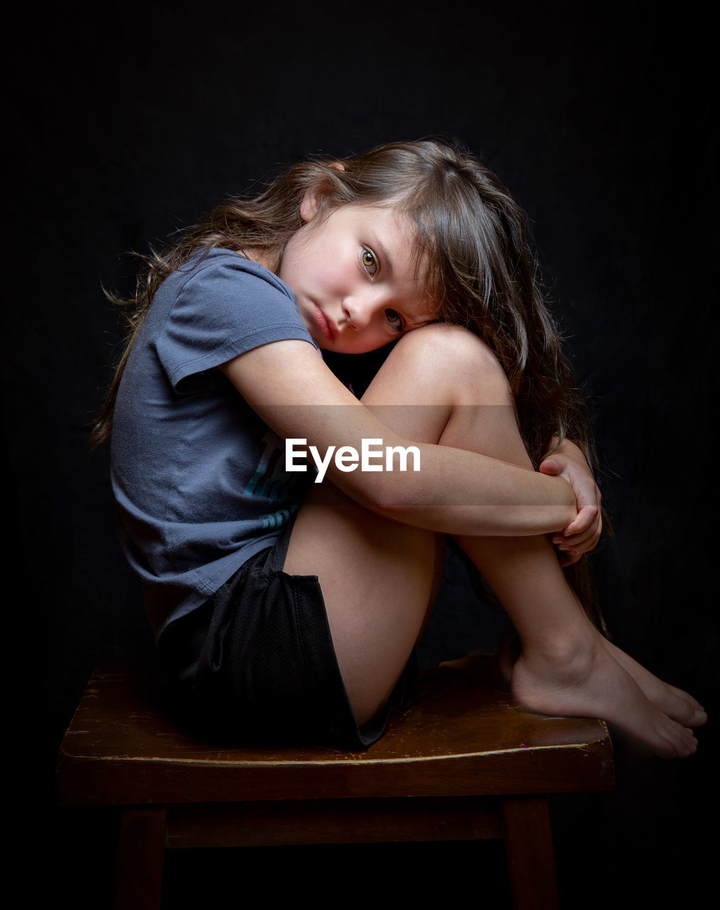 Girl sitting on chair against black background