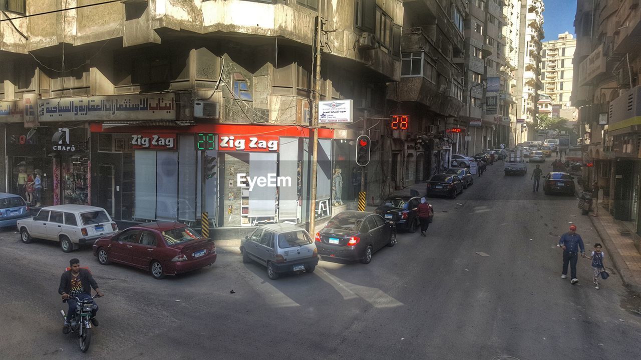 VEHICLES ON ROAD ALONG BUILDINGS