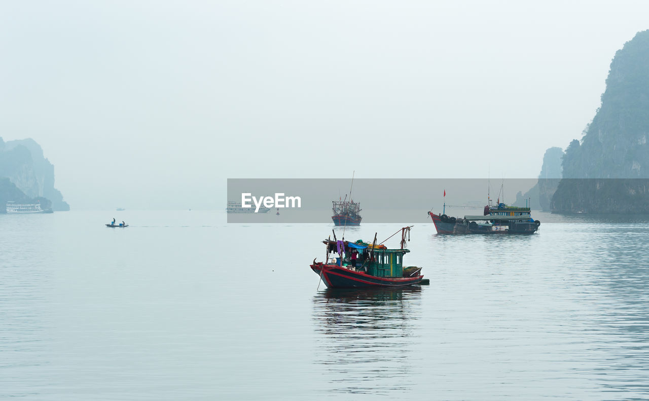 FISHING BOAT SAILING IN SEA AGAINST SKY