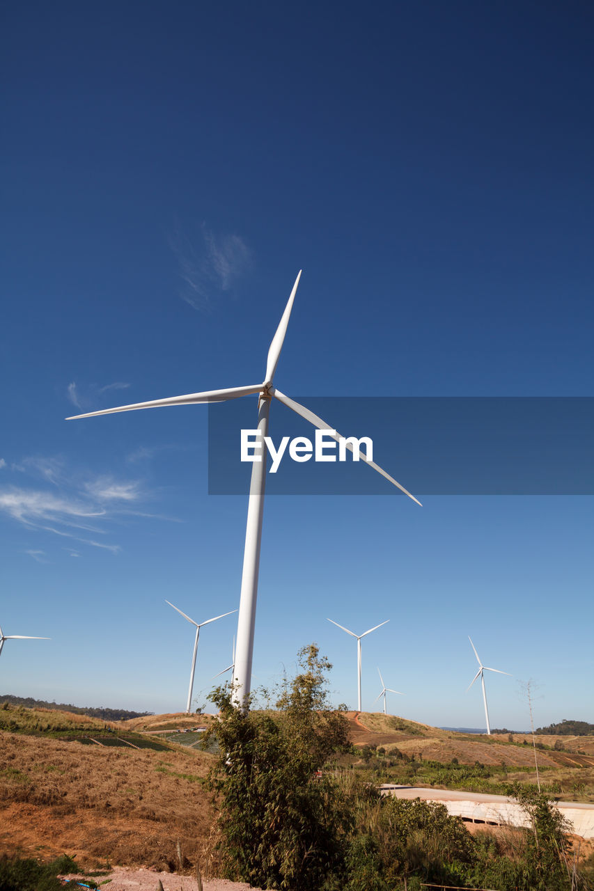 Wind turbines on field against blue sky