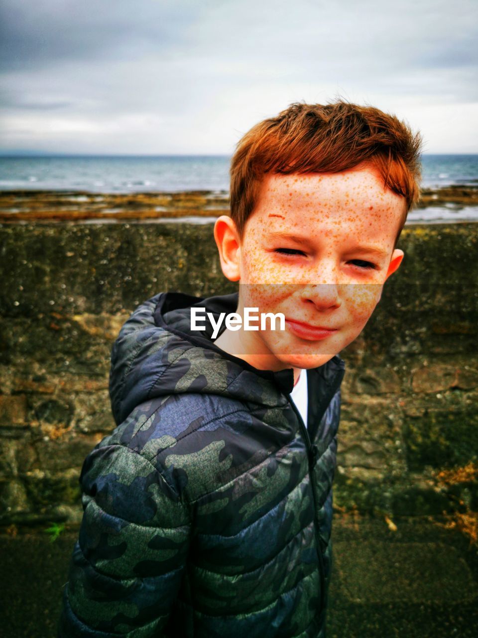 Portrait of boy with freckles on face against sea
