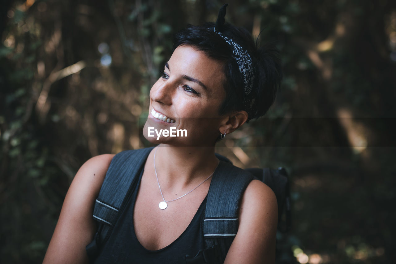 PORTRAIT OF SMILING WOMAN STANDING OUTDOORS