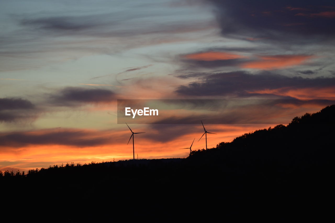 SILHOUETTE OF WIND TURBINES AGAINST DRAMATIC SKY