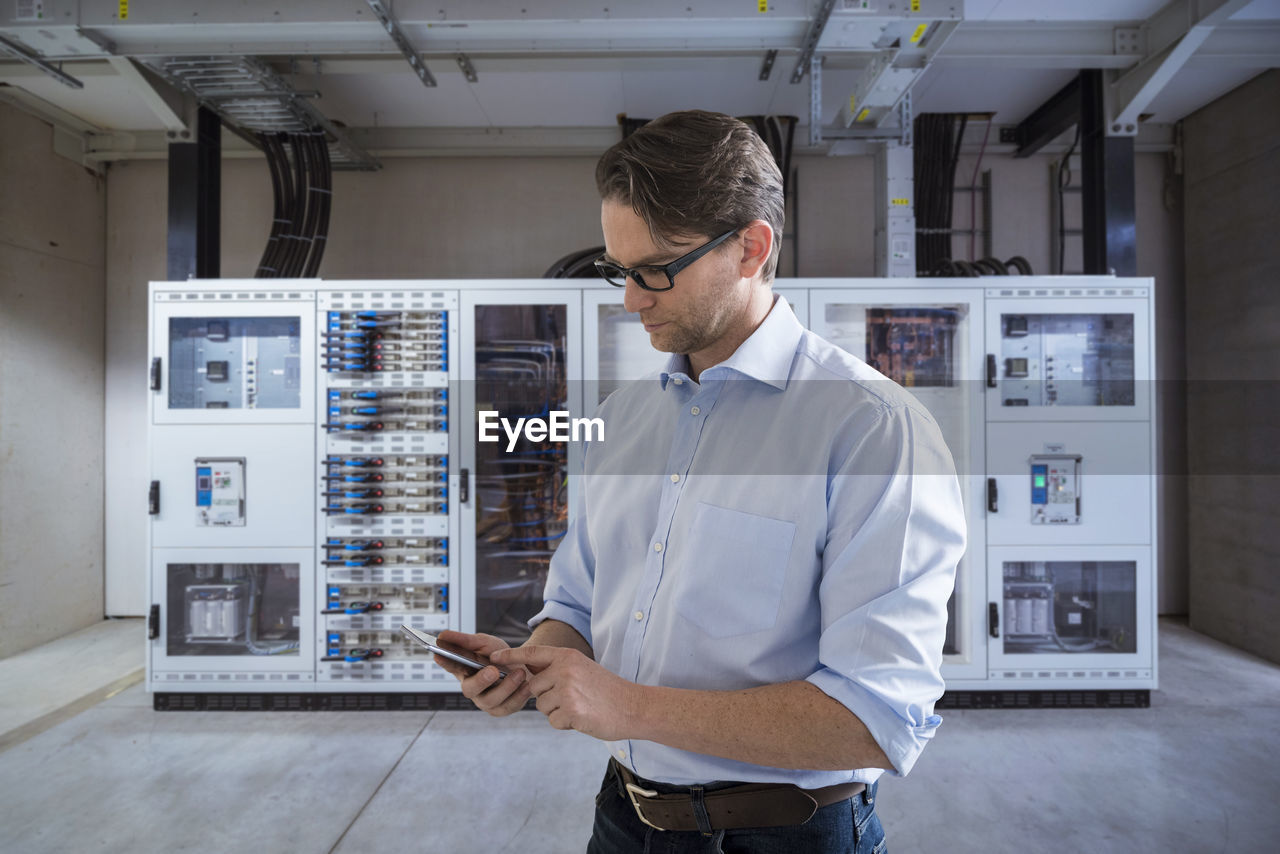 Businessman using smartphone in modern factory