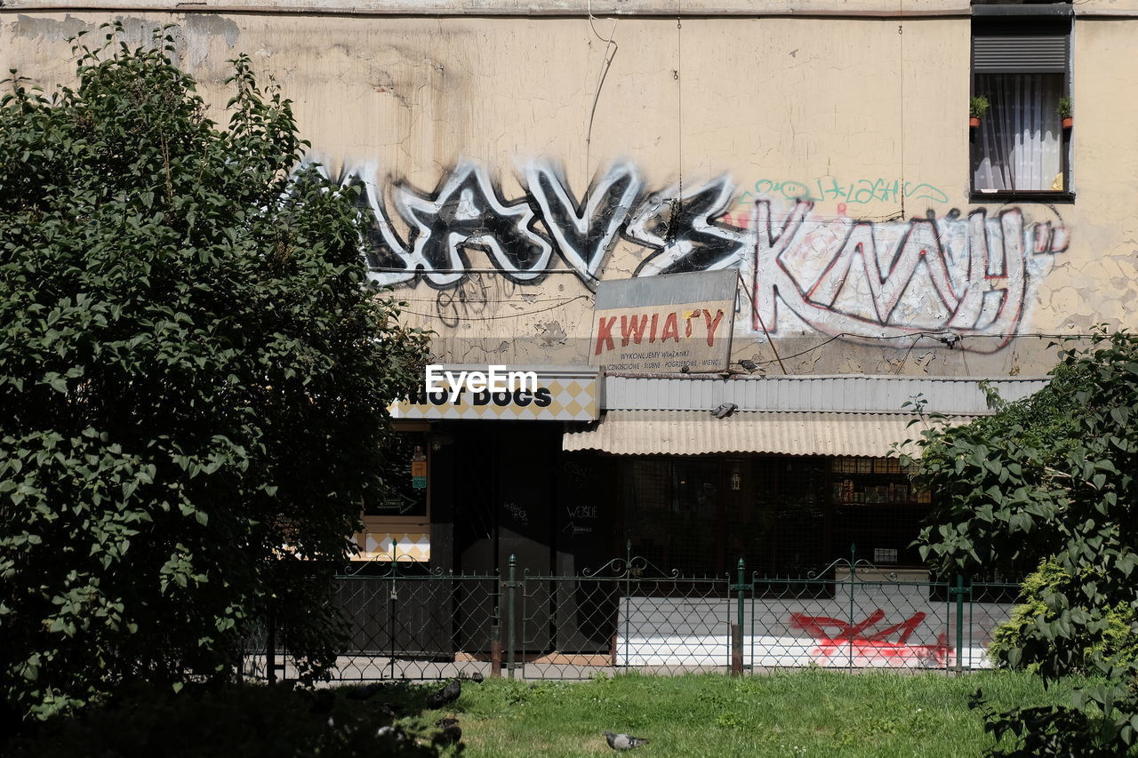 GRAFFITI ON WALL BY TREES AND BUILDING