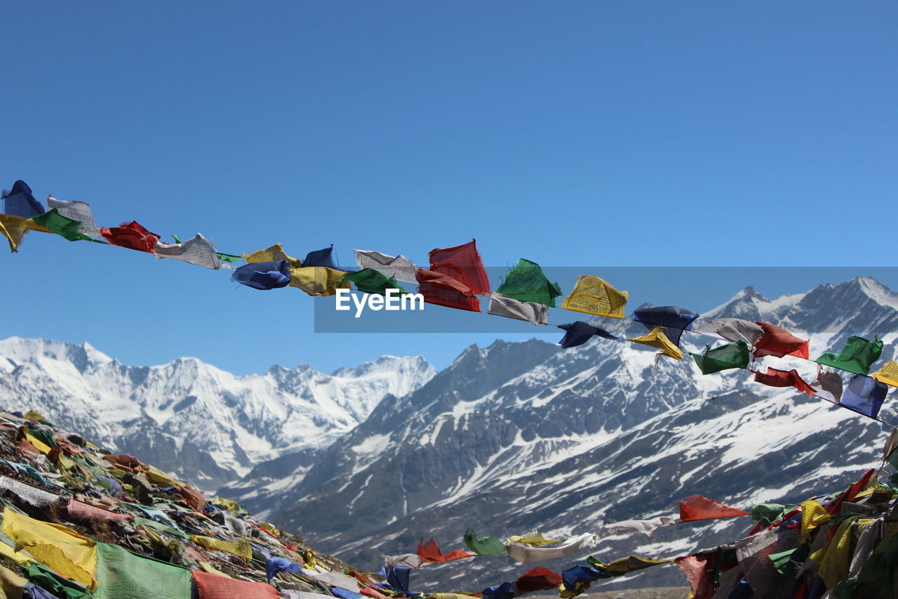 Low angle view of colorful prayer flags at himalayas against clear blue sky