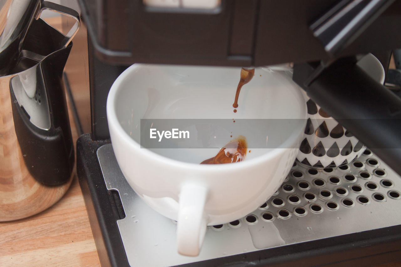 Close-up of espresso maker pouring drink in cup at cafe