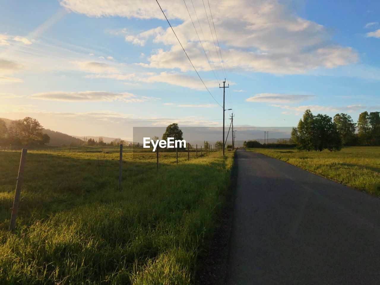 ROAD AMIDST FIELD AGAINST SKY DURING SUNSET