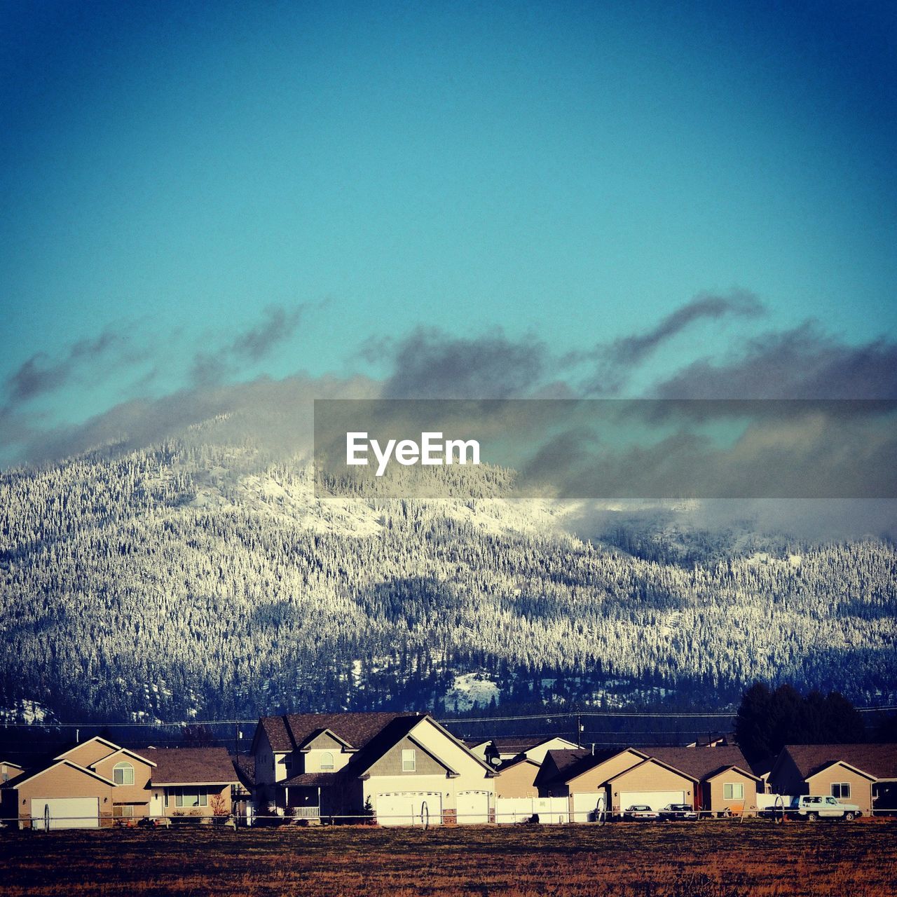 Houses by mountains against blue sky