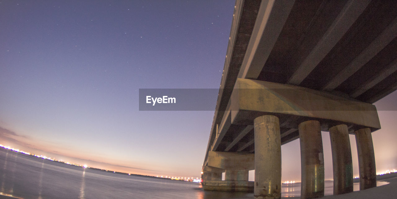 Fish-eye view of bridge over river against clear sky at dusk