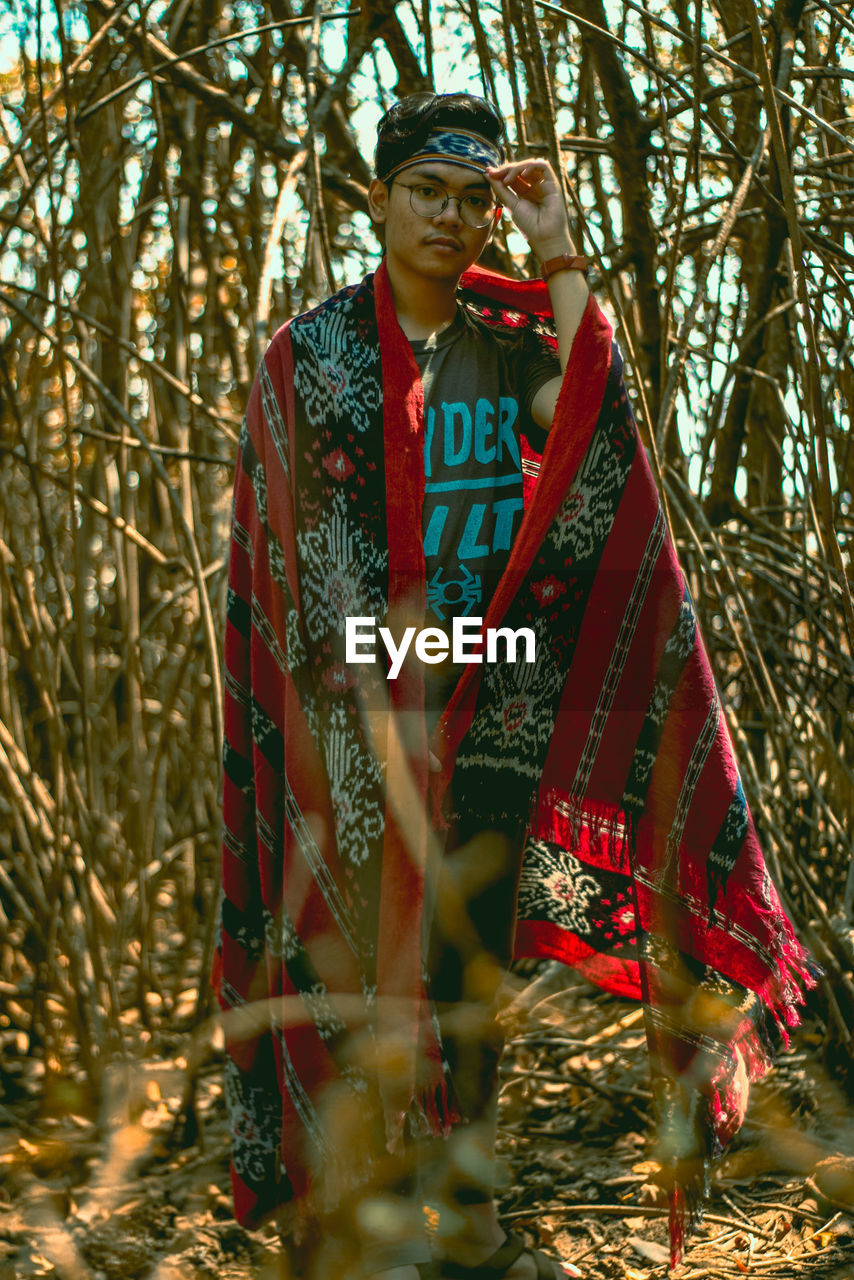 Portrait young man standing in forest