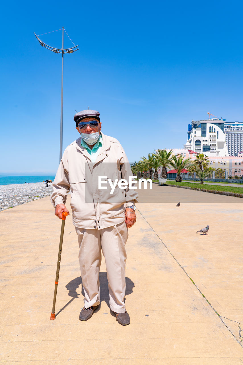 PORTRAIT OF MAN STANDING AGAINST BLUE SEA