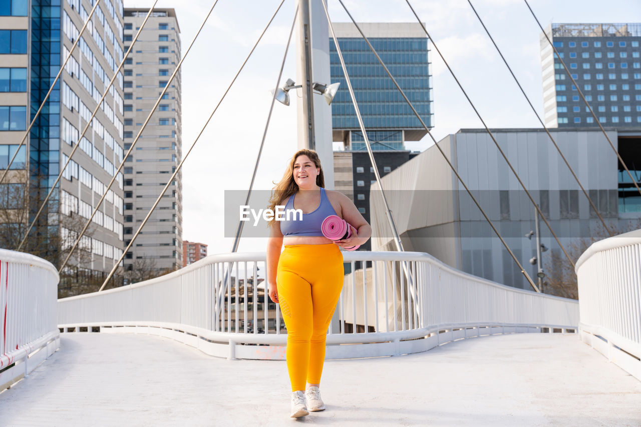 Full length of young woman walking on footbridge