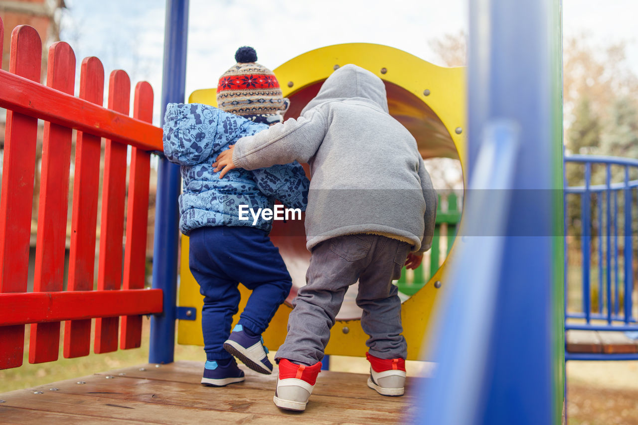 REAR VIEW OF FRIENDS ON PLAYGROUND