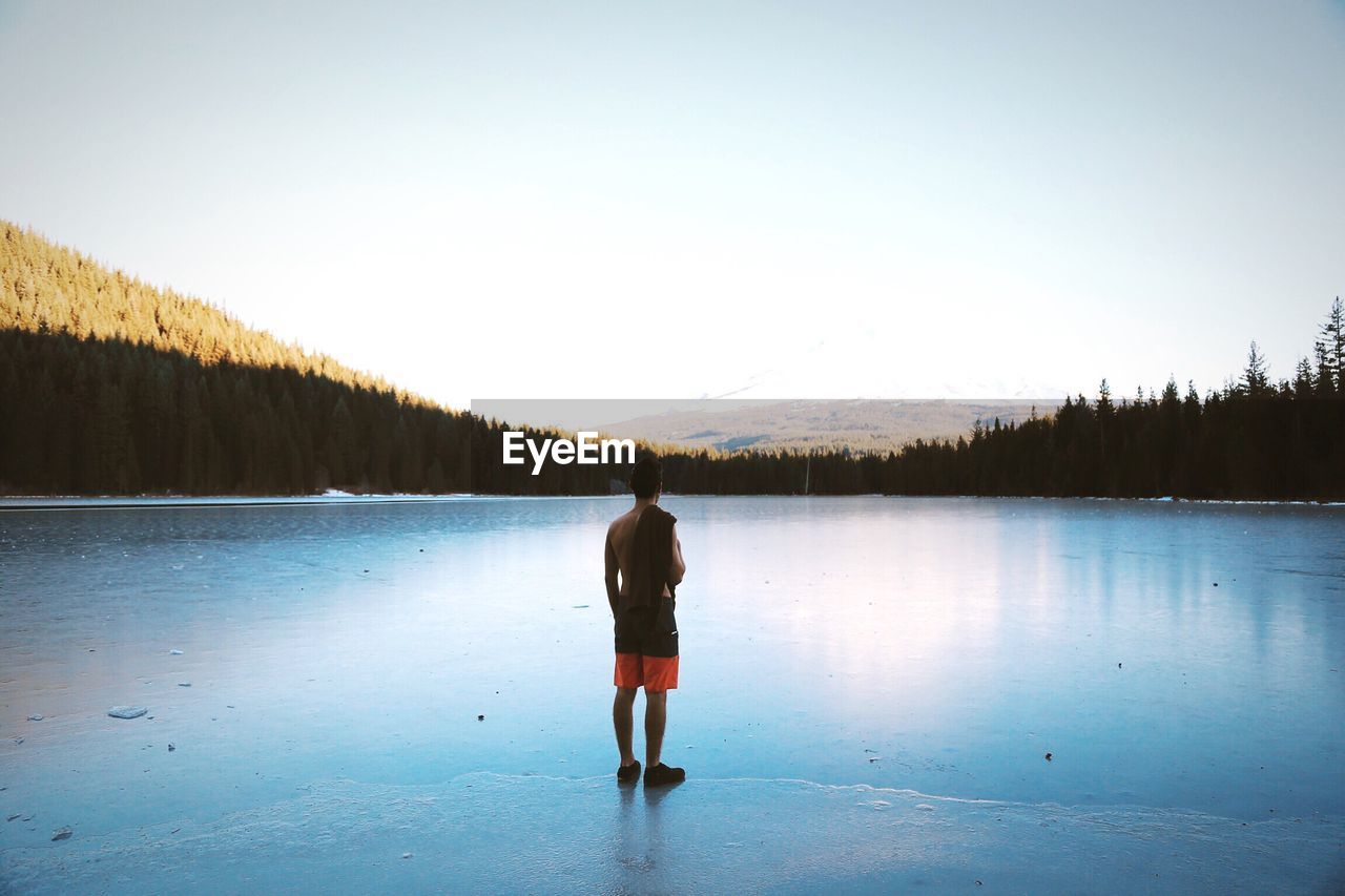 Man standing at shore of trillium lake against sky
