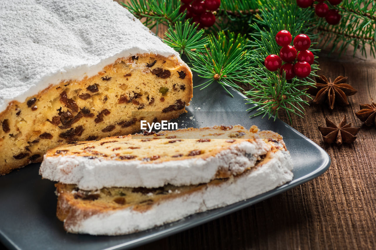 Christmas stollen on a plate with a rustic background and fir branch. 