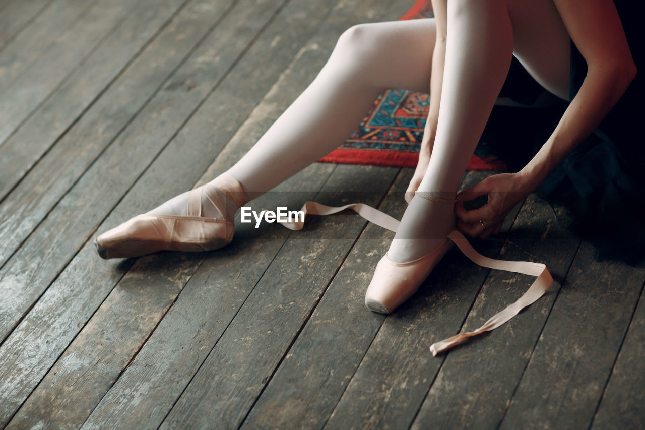 Low section of woman wearing ballet shoe