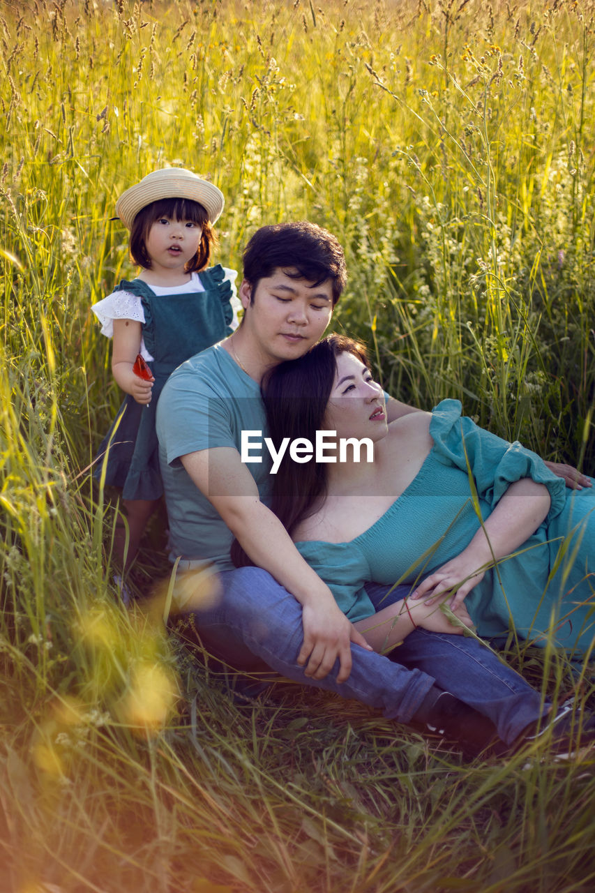 Korean family mom and father with a girl child daughter with candy lying on a green field in summer