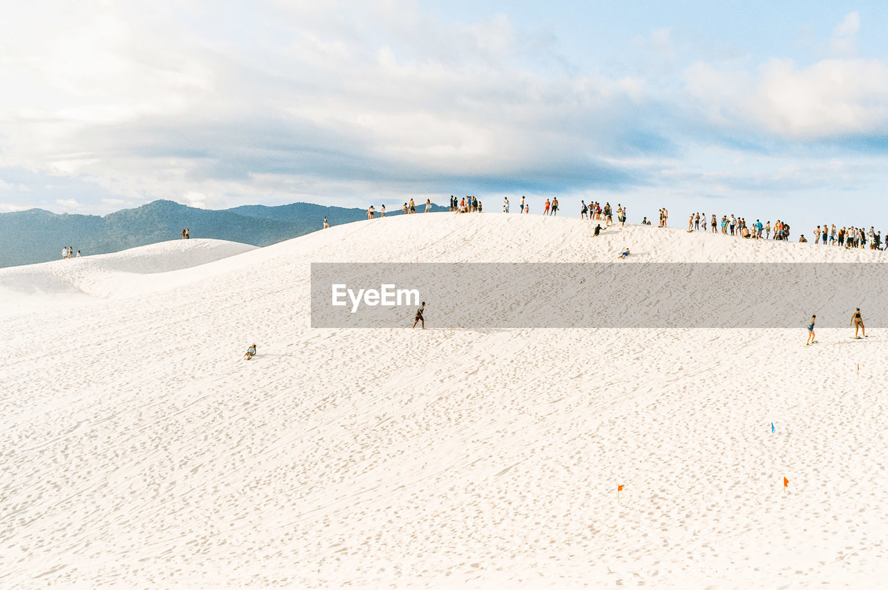 Panoramic view of people on beach against sky