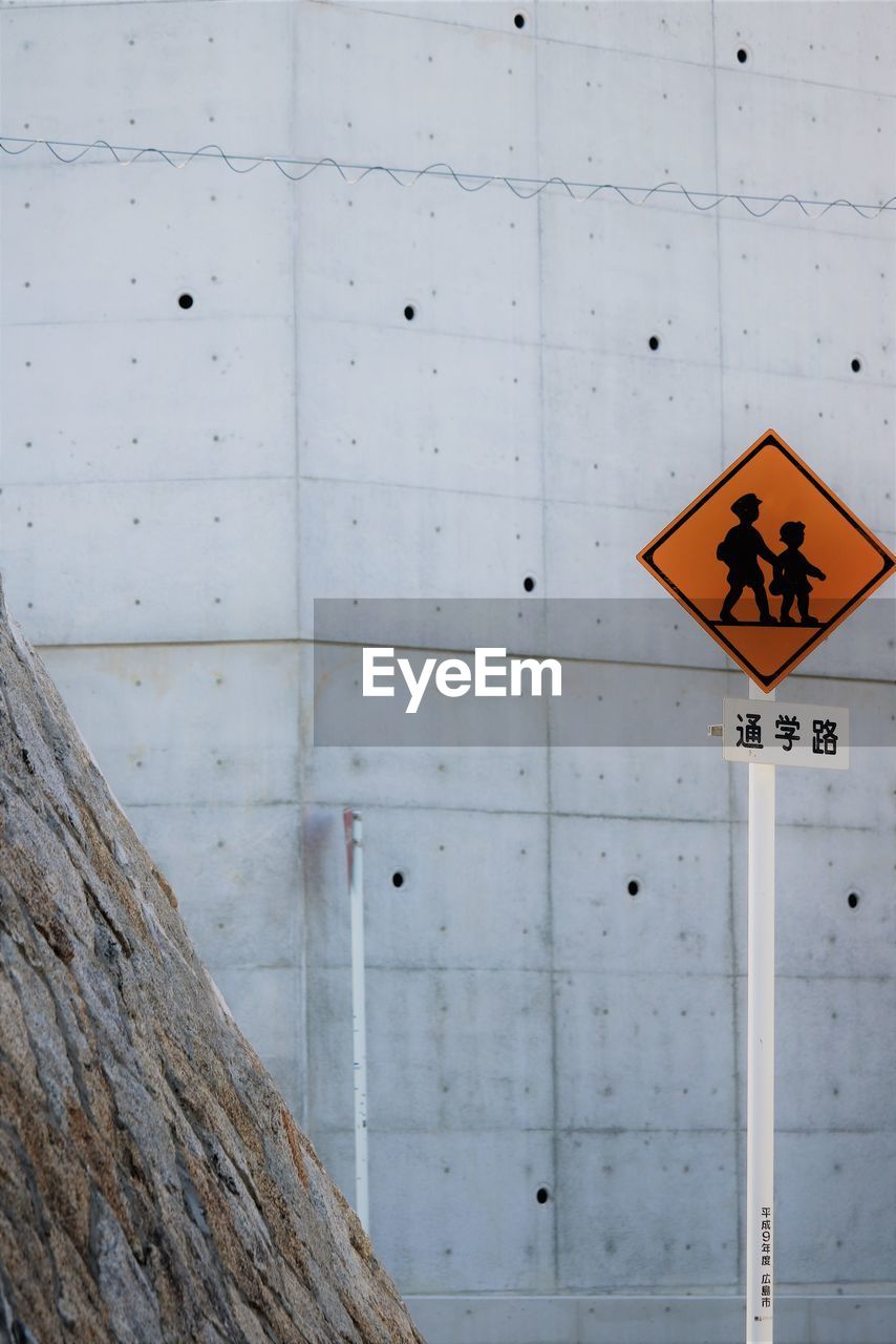 Close-up of children crossing road sign against wall