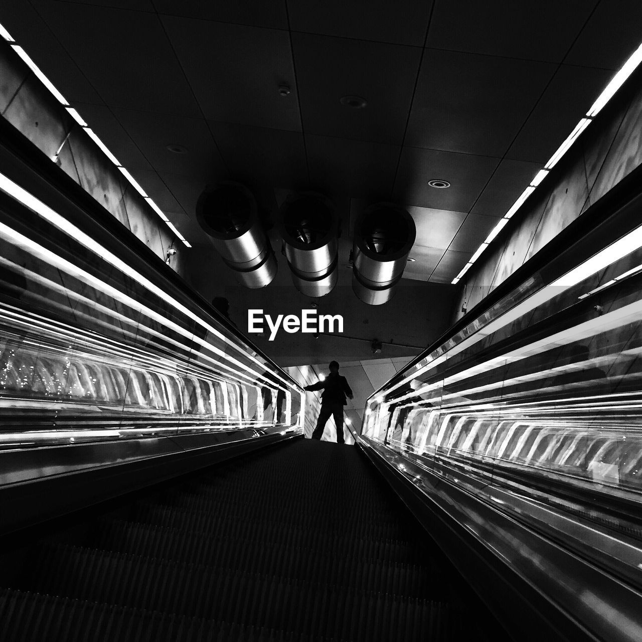 Low angle view of silhouette man standing on escalator in building