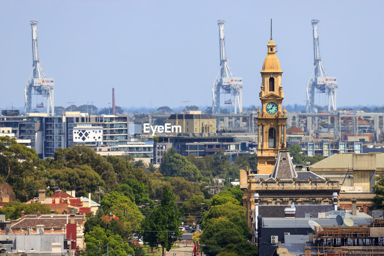 View of south melbourne town hall cityscape against freight cranes against sky