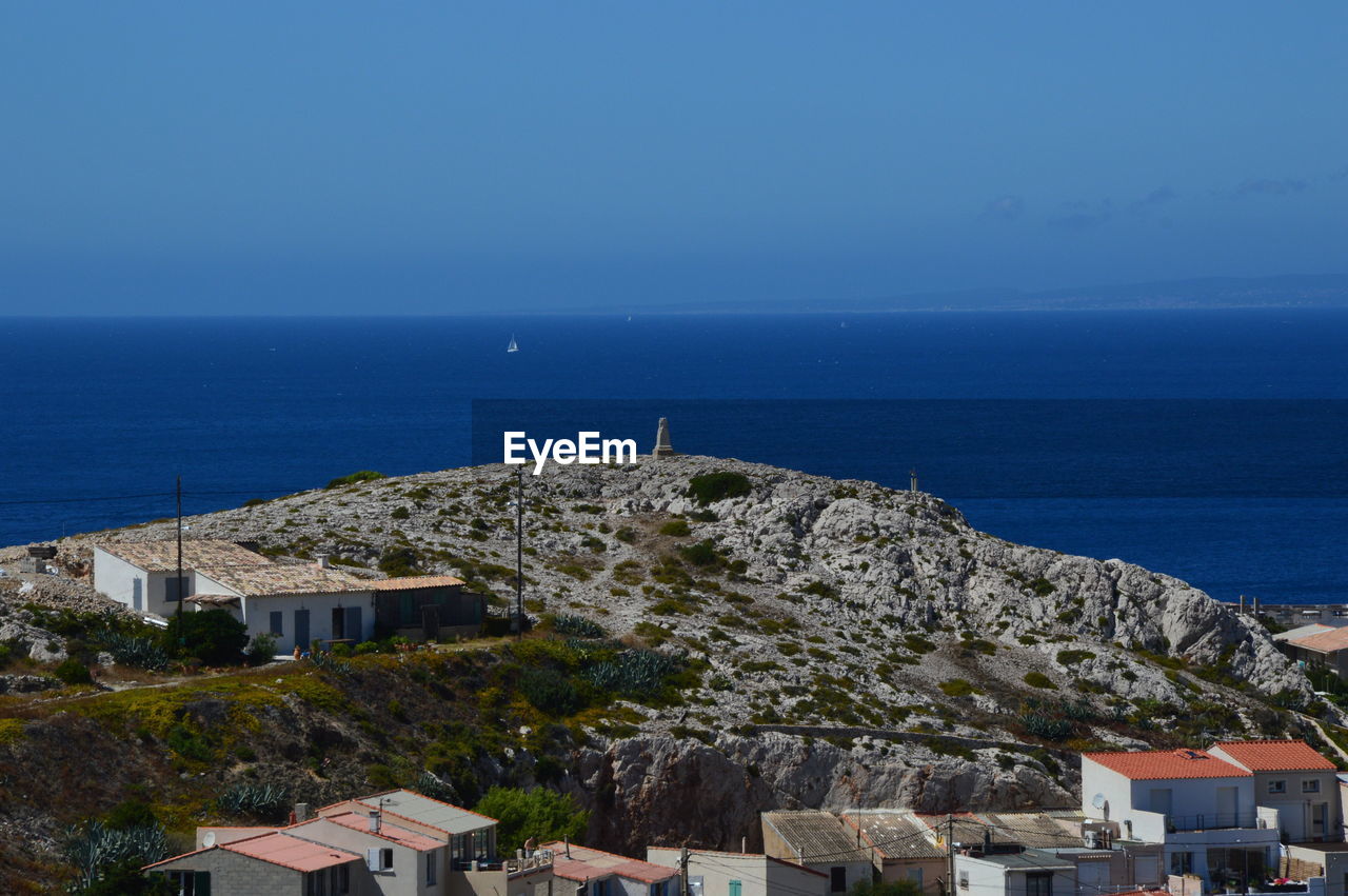 HIGH ANGLE VIEW OF HOUSES BY SEA AGAINST SKY