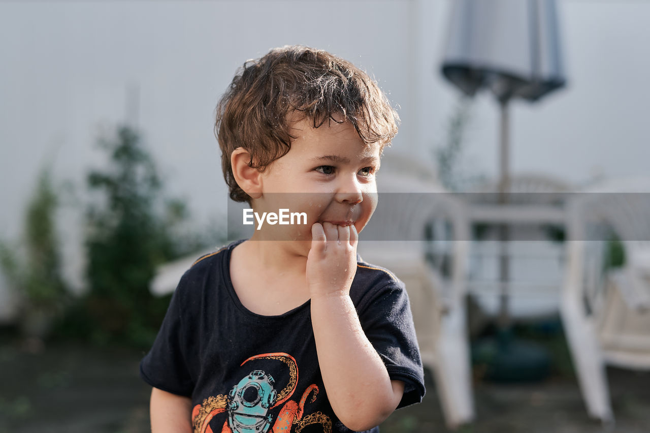 Little boy playing with a watering hose in the backyard