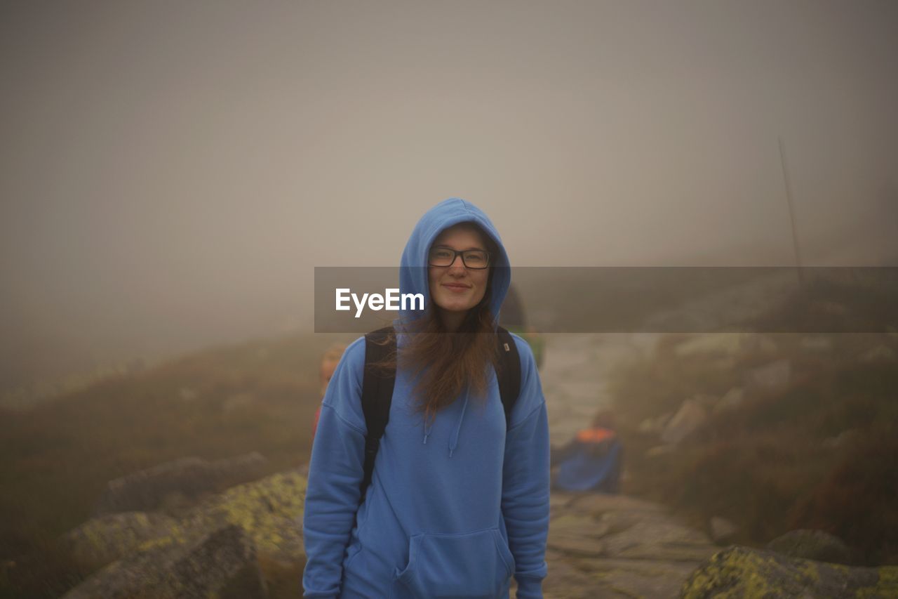 Portrait of smiling hiker standing against clear sky during winter