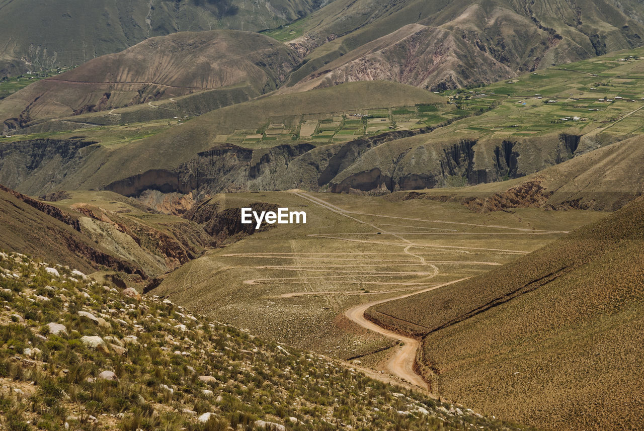 Dirt road on field against mountains