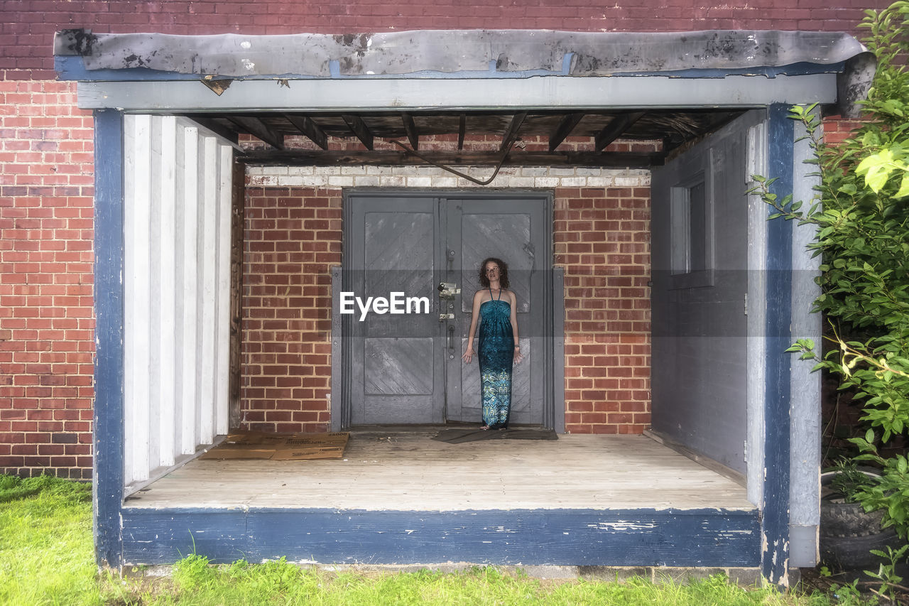 Woman standing against closed door of abandoned house