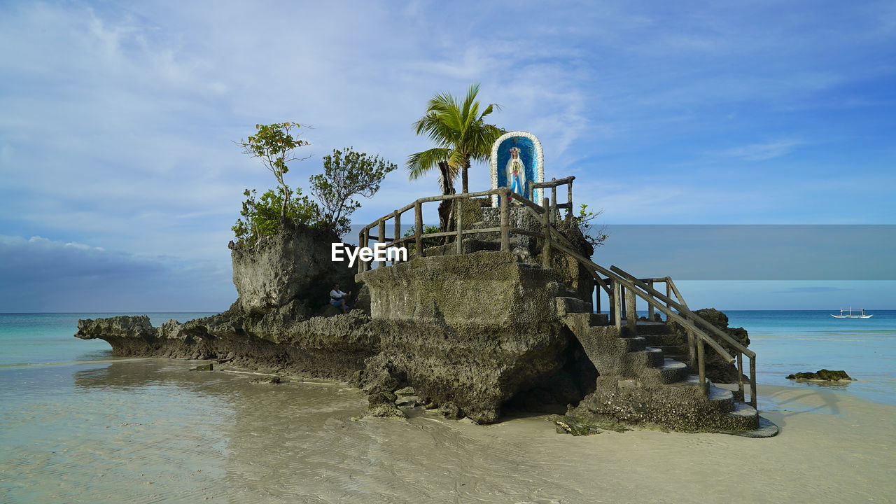 Virgin mary statue on built structure at beach against sky