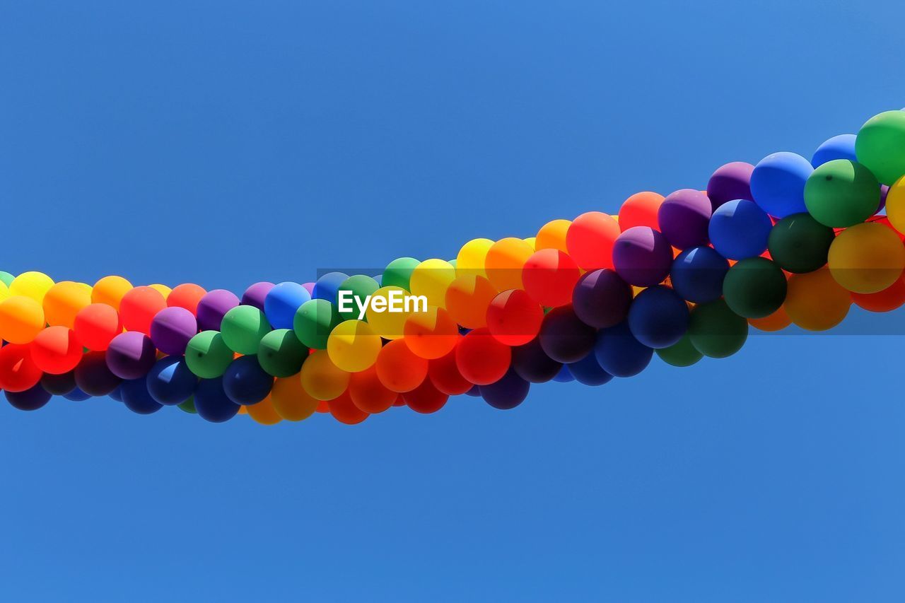 LOW ANGLE VIEW OF BALLOONS AGAINST BLUE SKY