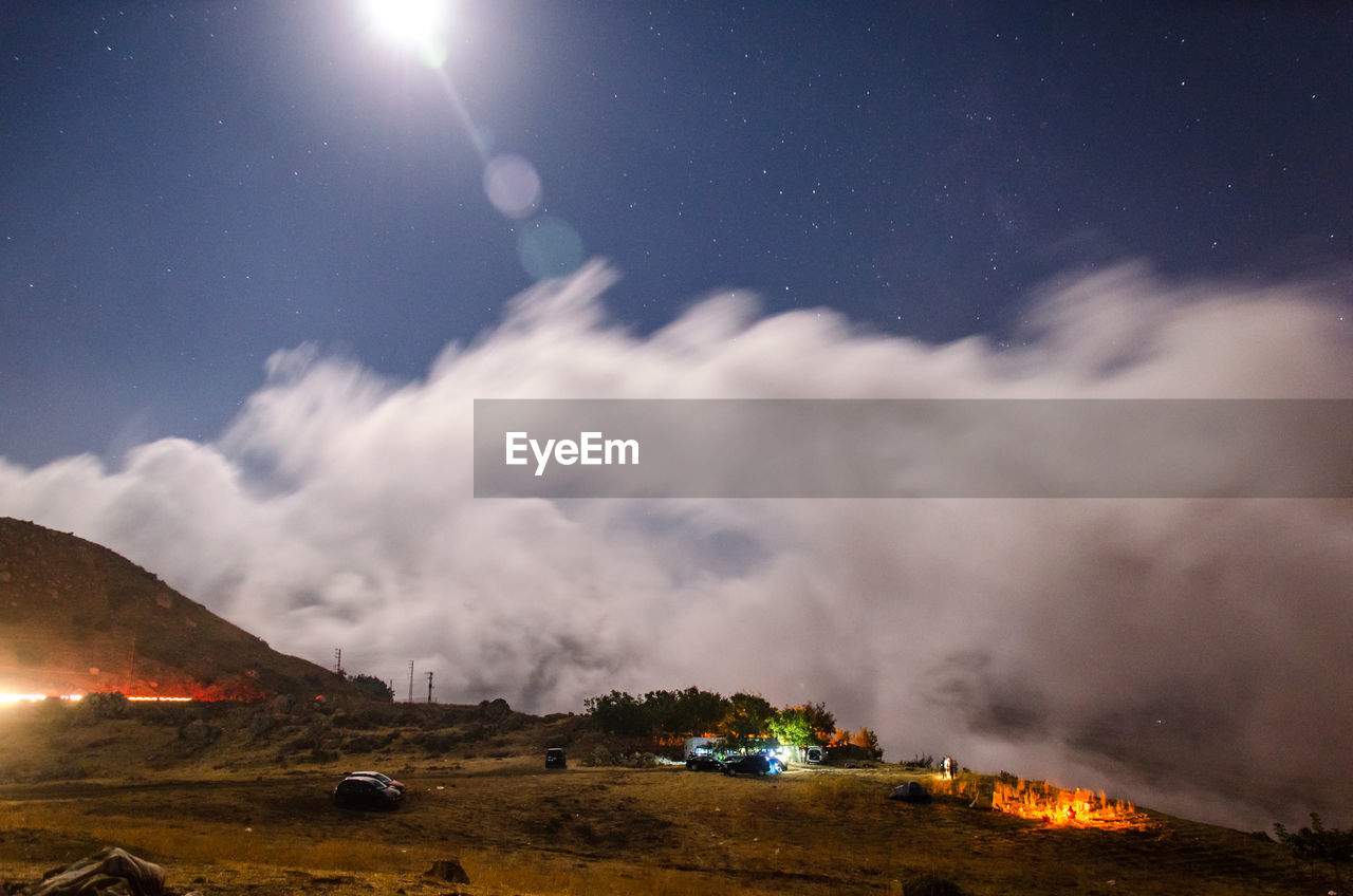 PANORAMIC VIEW OF ILLUMINATED LAND AGAINST SKY