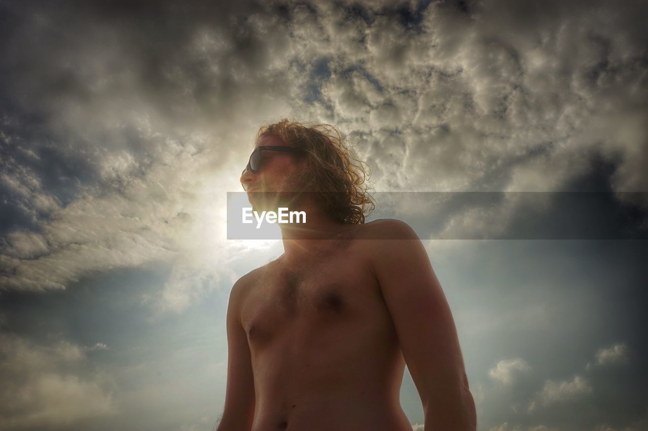 LOW ANGLE VIEW OF MAN STANDING AGAINST SKY