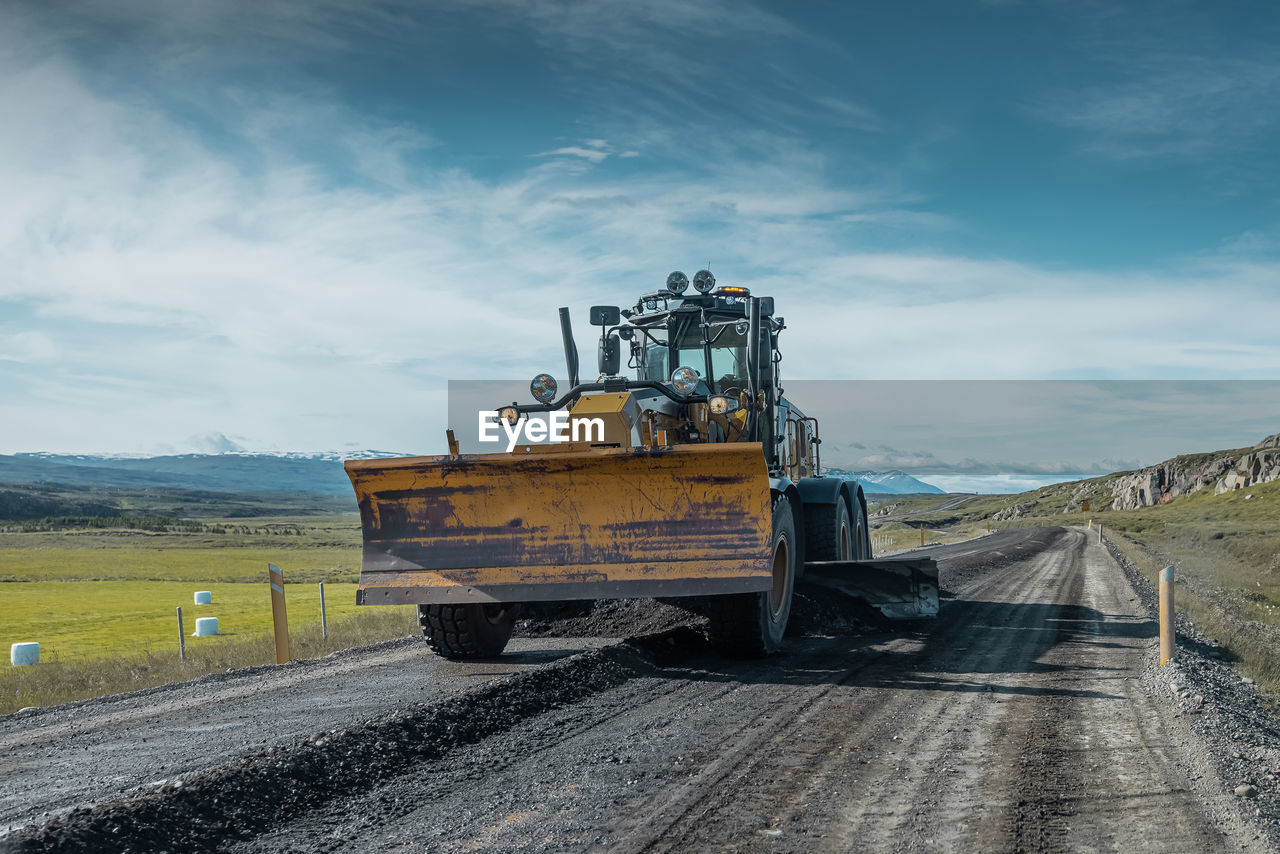 road by field against sky