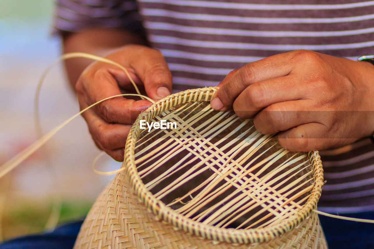 Midsection of man making wicker decoration