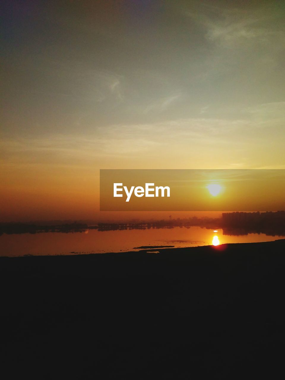 View of lake against orange sky at sunset