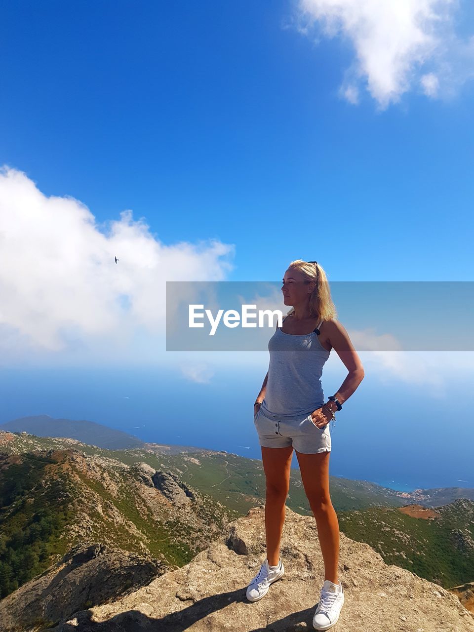 Full length of woman standing by cliff against sky