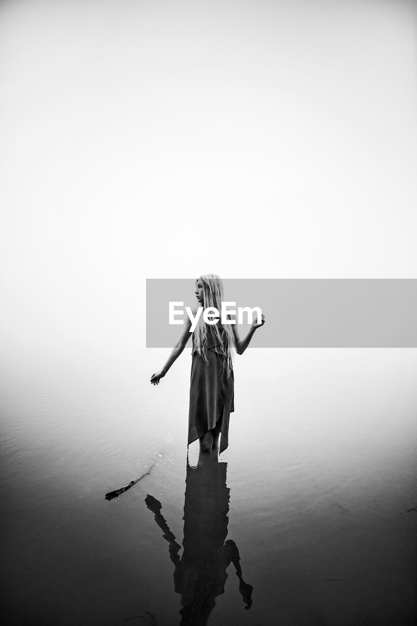 Woman standing in sea against clear sky