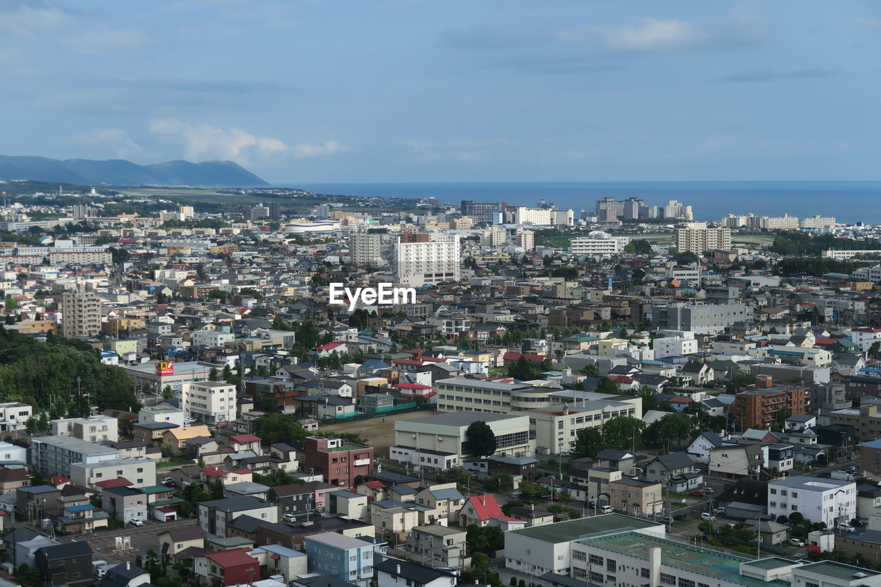 High angle view of townscape by sea against sky