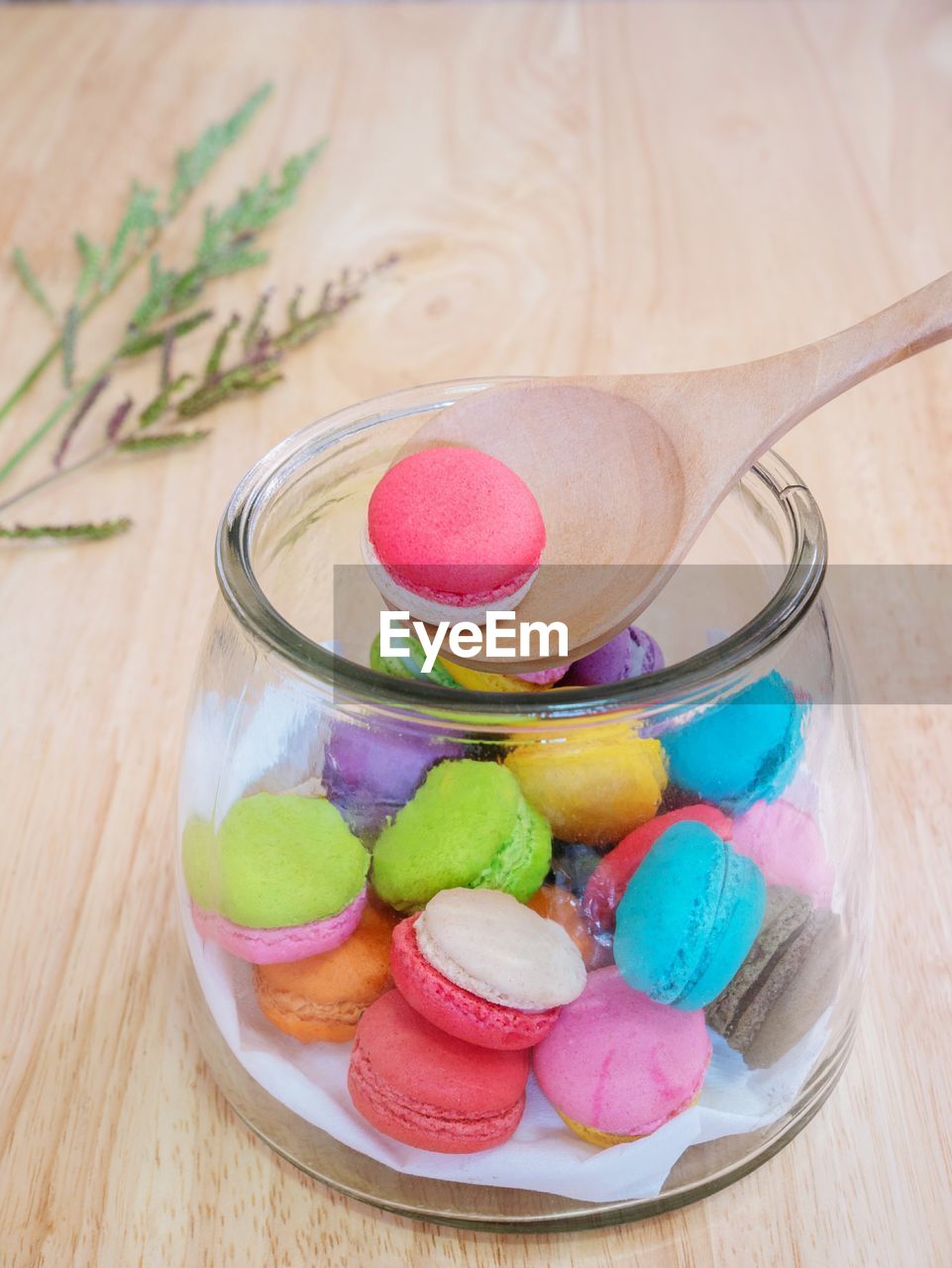 High angle view of multi colored macaroon with wooden spoon in jar